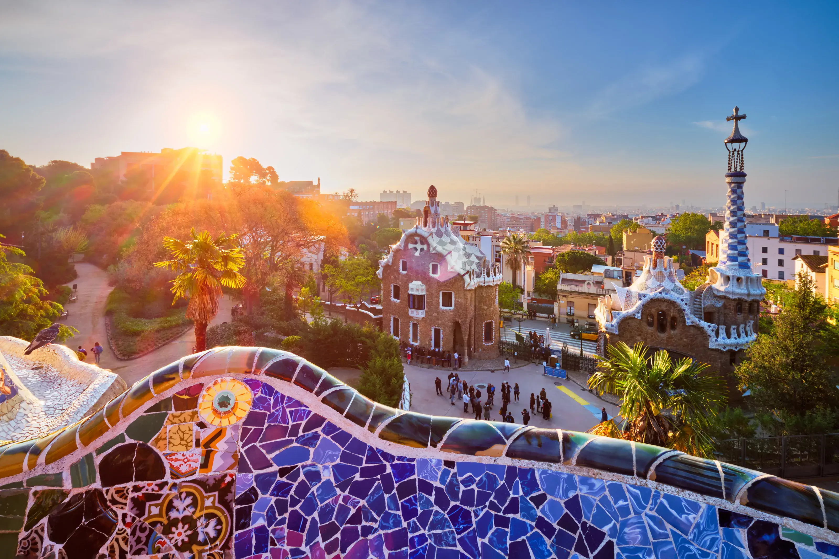 Barcelona city view from Guell Park with colorful mosaic buildings in tourist attraction Park Guell in the morning on sunrise. Barcelona, Spain. Barcelona city view from Guell Park