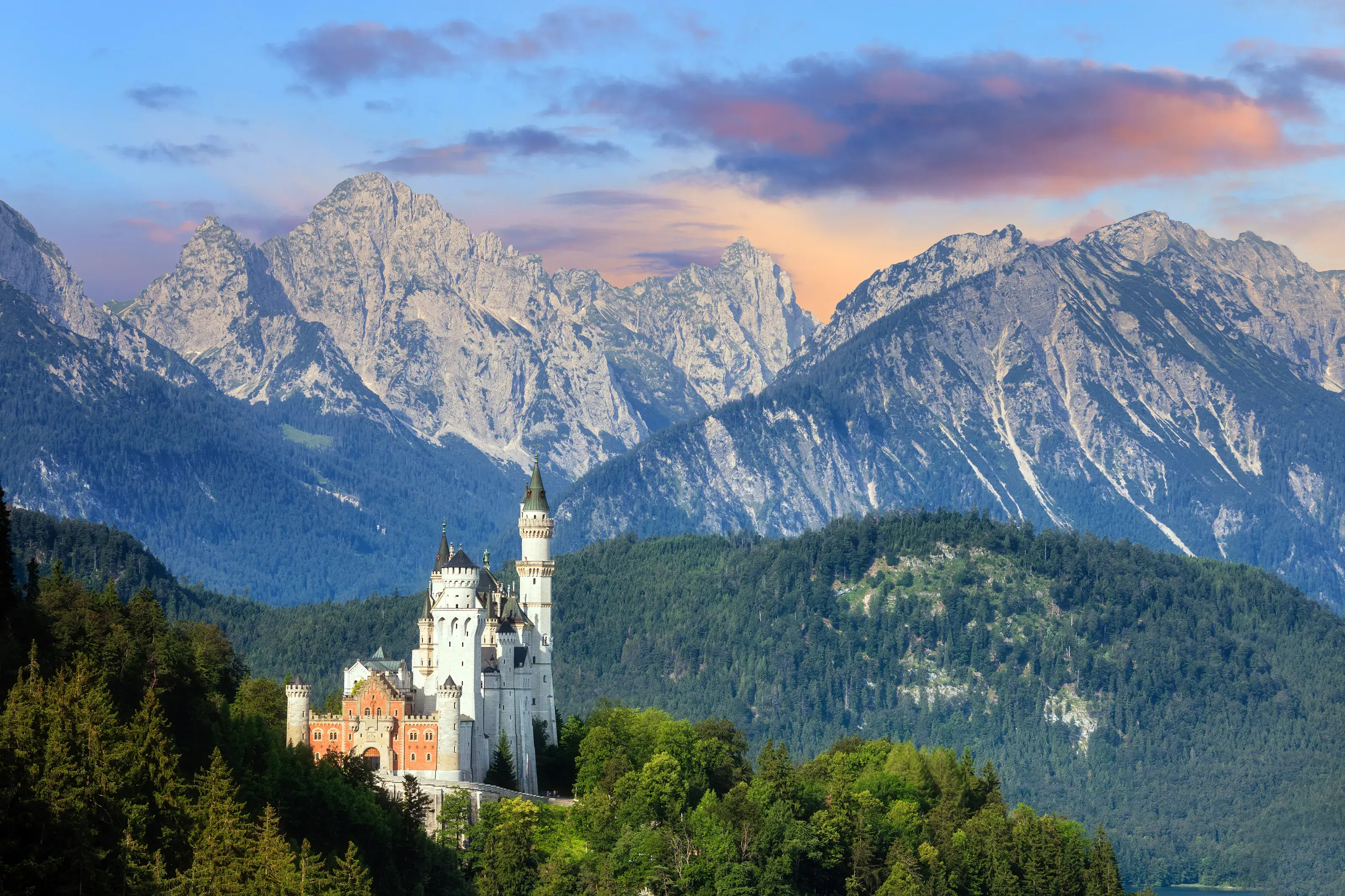 The iconic Neuschwanstein Castle in Bavaria, Germany, set against the dramatic backdrop of the soaring Alps at sunset.
