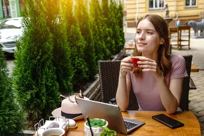 Young woman using laptop pc in a cafe on a summer terrace.. young woman using laptop in a cafe on a summer terrace